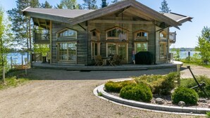 A two-story log cabin with a balcony, large windows, and a gravel driveway. - Villa pyöriäinen by Interhome (Kerimäki)