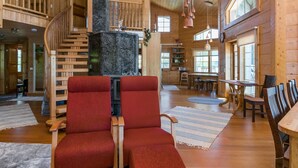 A spacious wooden interior with a fireplace, a dining area, and a staircase. - Villa pyöriäinen by Interhome (Kerimäki)