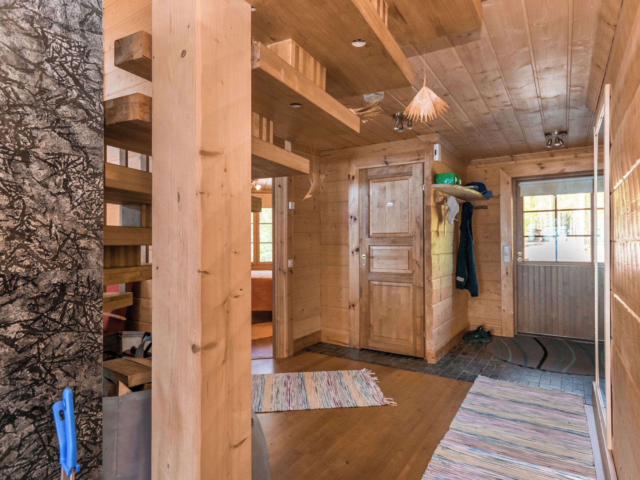 A wooden interior with a door, a shelf, and a hanging light fixture.