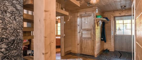 Un intérieur en bois avec une porte, une étagère et un luminaire suspendu.