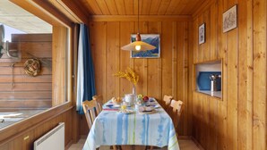 A wooden interior with a dining table set for breakfast, a radiator, and a window with curtains. - Mogador 13 by Interhome (Verbier)
