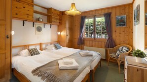 A cozy wooden room with a bed, a chair, a dresser, and a window with curtains. - Mogador 13 by Interhome (Verbier)