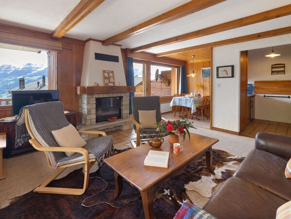 Un salon chaleureux avec une cheminée, un coin repas et une vue sur les montagnes.