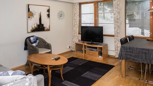 Una sala de estar con televisor, una mesa de comedor, un sofá y una silla.