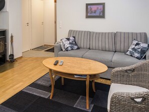 A cozy living room with a sofa, a round wooden coffee table, and a wicker chair.