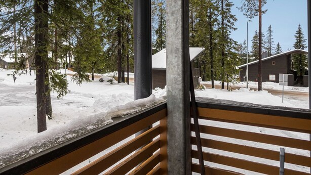 Un banco de madera con vistas a un paisaje nevado, con árboles y un edificio al fondo.