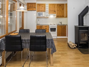 Eine moderne Küche mit Holzschränken, einem Herd und einem Essbereich mit Tisch und Stühlen.