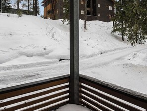 A snow-covered slope with a wooden railing and a building in the background.