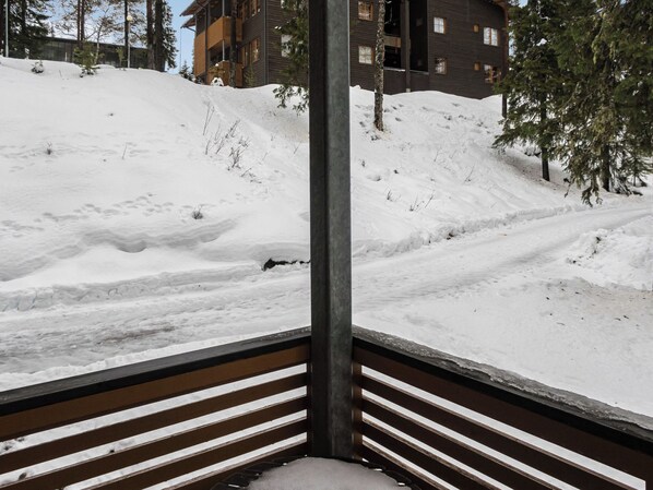A snow-covered slope with a wooden railing and a building in the background.