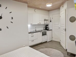 A compact kitchen with white cabinets, a microwave, a coffee maker, and a clock on the wall. - Weekend duetto by Interhome (Sotkamo)