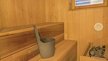 A wooden sauna bench with a bucket and a sauna heater.