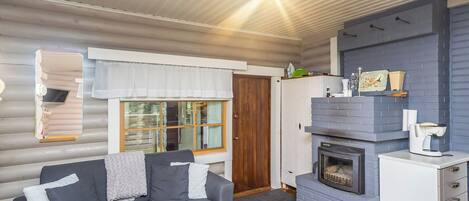 A compact living space with a sofa, a fireplace, and a small kitchen area.