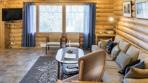 A log cabin interior with a sofa, chairs, a dining table, and a TV. - Rinnetupa by Interhome (Kuusamo)