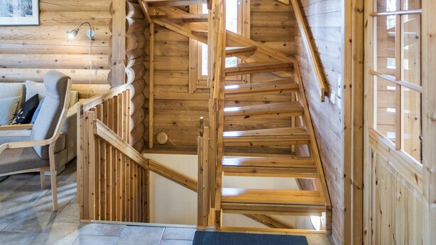 A wooden staircase in a log cabin interior with a sofa and a framed picture on the wall. - Rinnetupa by Interhome (Kuusamo)