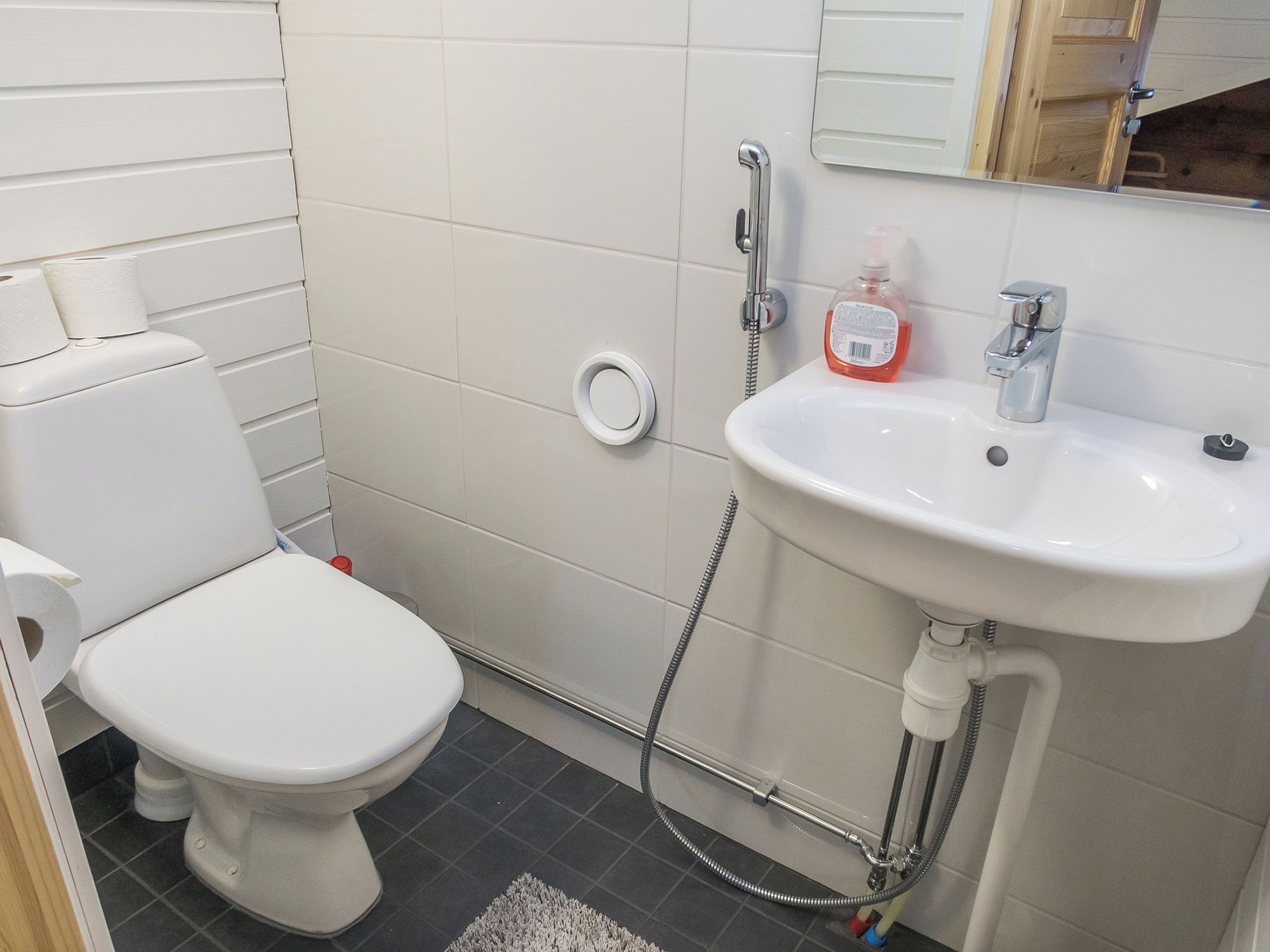 A small bathroom with a toilet, sink, and shower.