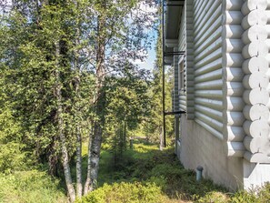 Un bâtiment dont l’extérieur est conçu comme une cabane en rondins, entouré d’arbres et de verdure.