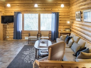 A log cabin interior with a sofa, chairs, a coffee table, and a television. - Rinnetupa by Interhome (Kuusamo)