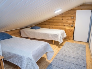Une petite chambre confortable avec deux lits, une armoire en bois et un bureau.