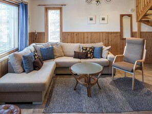 A modern living room with a sectional sofa, a round glass table, and a wooden chair. - Rinnetupa by Interhome (Kuusamo)