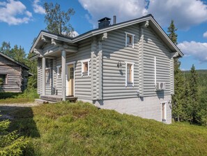 A log cabin with a porch, a chimney, and a view of the surrounding forest. - Rinnetupa by Interhome (Kuusamo)