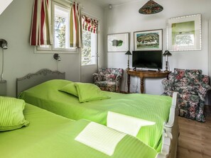 Un dormitorio con dos camas, una televisión y dos sillones.