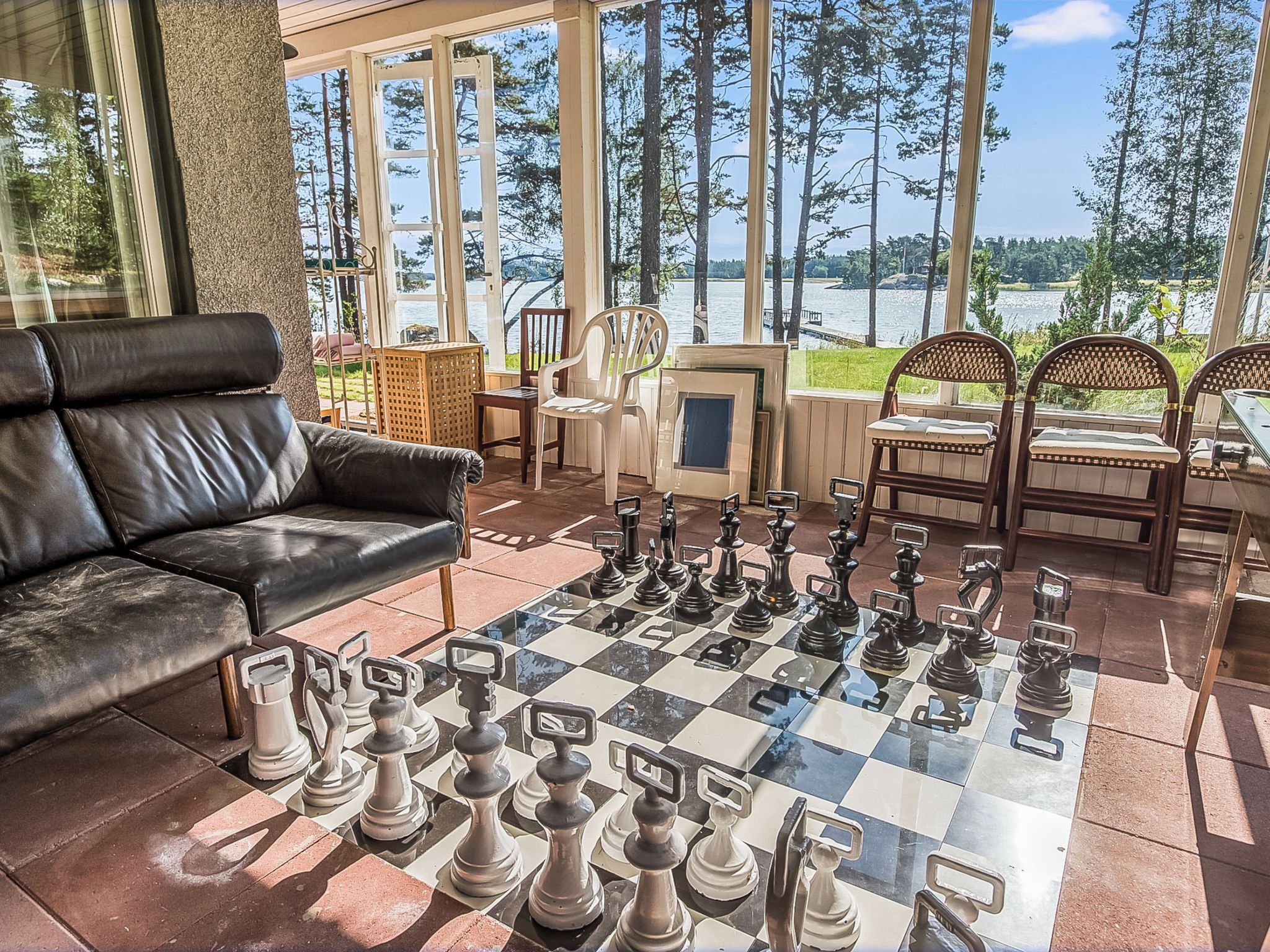 A chessboard set up on a patio with a view of a lake and trees.