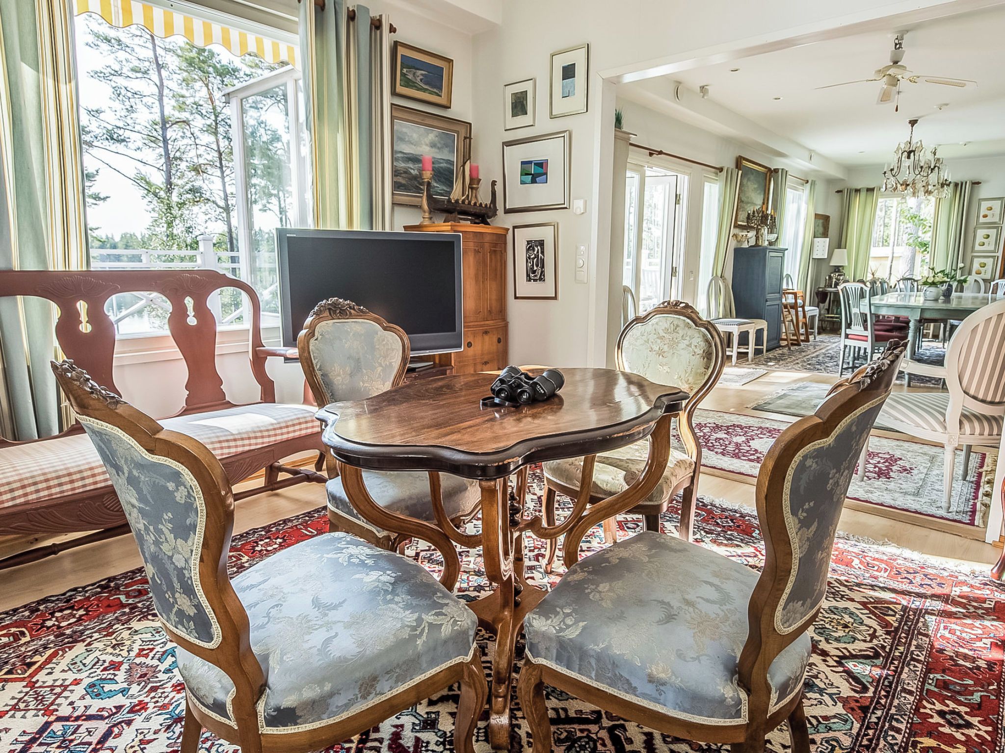 Comedor con una mesa redonda, sillas ornamentales y un televisor.