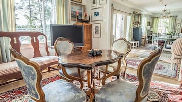 Comedor con una mesa redonda, sillas ornamentales y un televisor.
