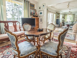 Un coin repas avec une table ronde, des chaises décorées et un téléviseur.