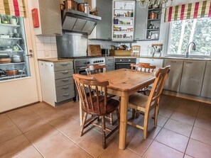 Une cuisine avec une table et des chaises en bois, un poêle et des placards.