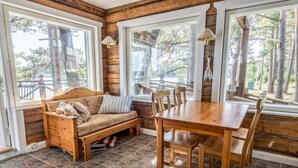 Ein gemütliches Blockhaus-Interieur mit einer hölzernen Bank, einem Esstisch aus Holz und einem Boden mit Steinplatten.