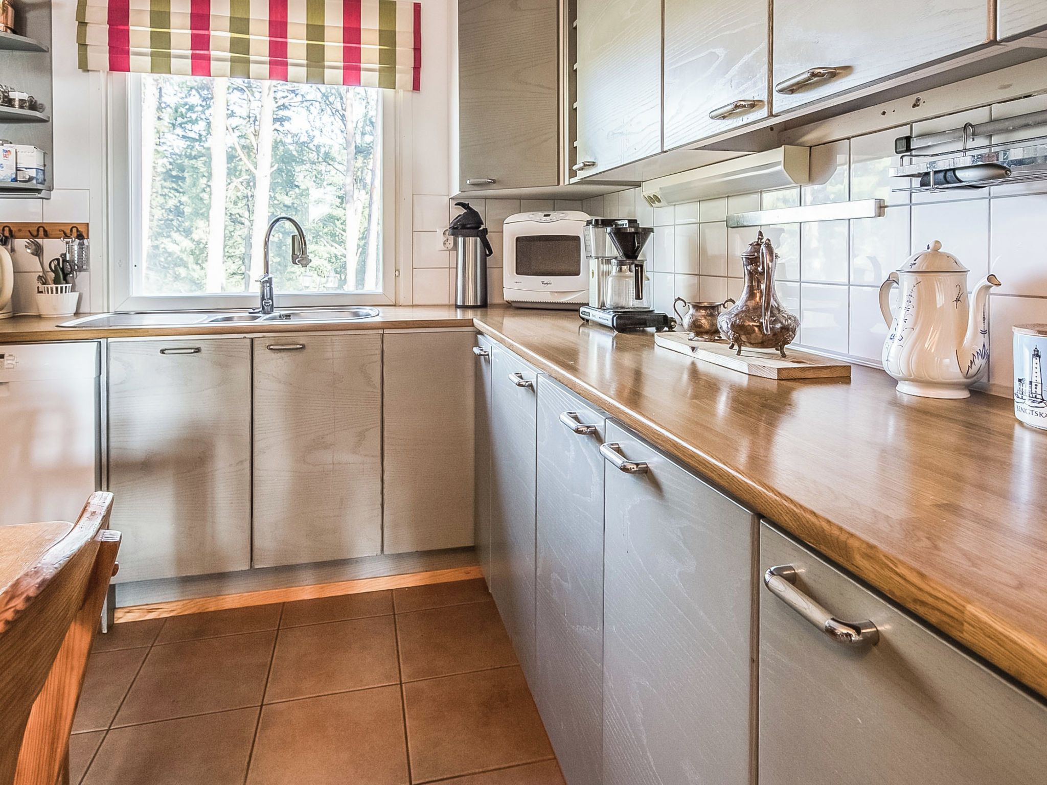 Eine Küche mit Fenster, Spüle, Schränken und Arbeitsplatte.