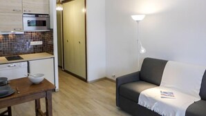 Un espace de vie compact comprenant un coin cuisine, un canapé et une lampe sur pied.