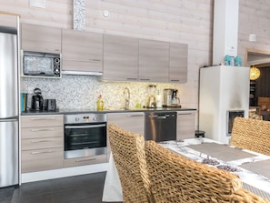 A modern kitchen with stainless steel appliances, a built-in oven, and a dining area with wicker furniture.