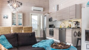 Een moderne woonkamer met een donkere bank, een blauwe tafel en een kroonluchter.