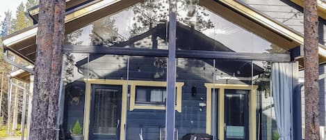 Una baita con portico coperto, una porta scorrevole in vetro e un piccolo angolo salotto all'aperto.