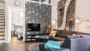 Een moderne woonkamer met een grijze bank, een televisie en een behang met patroon.