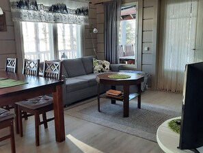 Een woonkamer met een bank, salontafel en eettafel.