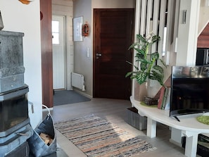 A living room with a fireplace, a television, a plant, and a door leading to another room. - Loisteranta by Interhome (Ähtäri)