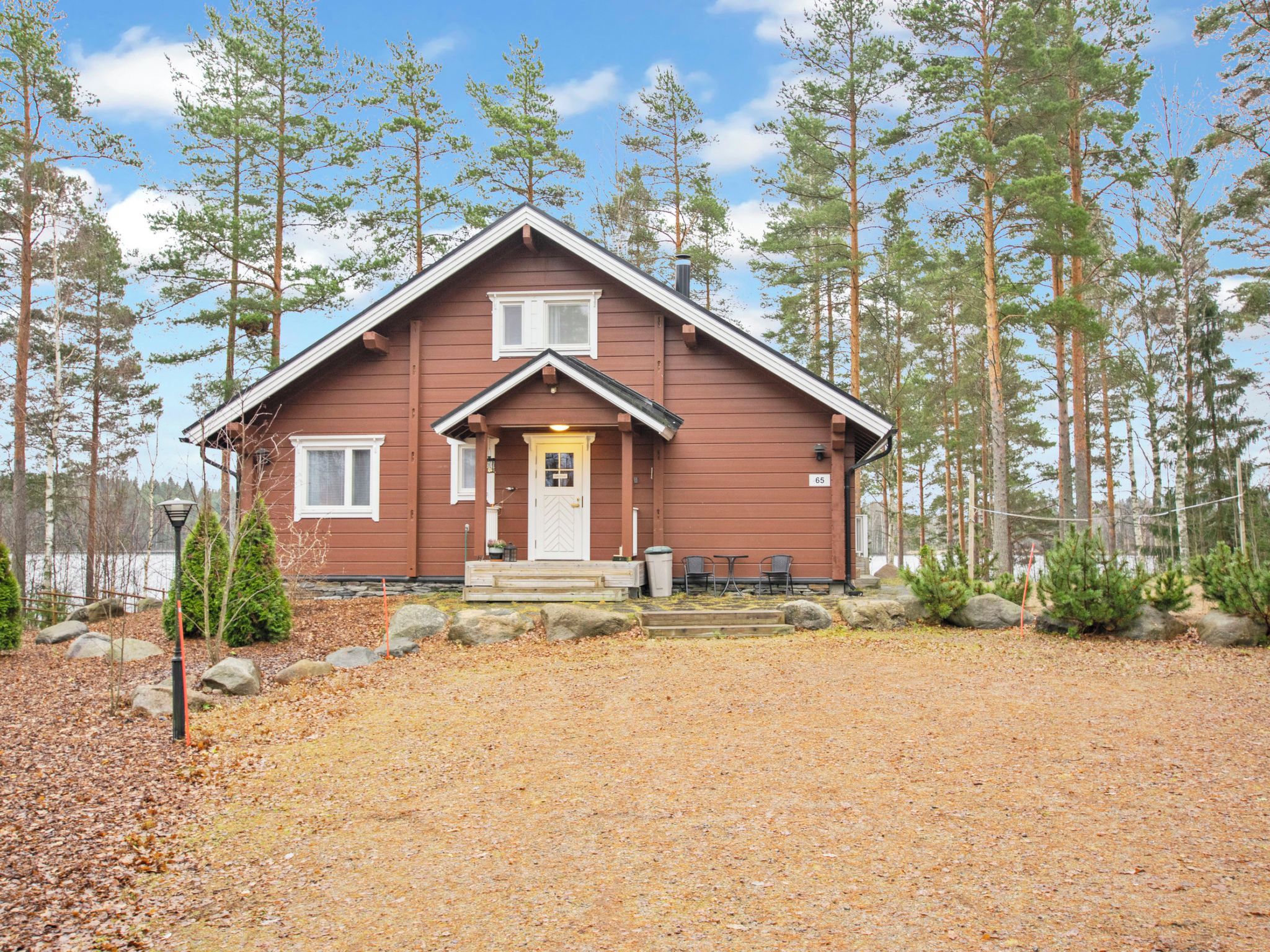 A two-story cabin with a front porch, surrounded by a forest.