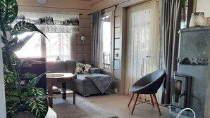 Een moderne woonkamer met een bank, een ronde salontafel, een zwarte stoel, een open haard en een grote plant.