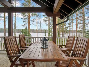 A wooden deck with a table and chairs, overlooking a lake with trees. - Loisteranta by Interhome (Ähtäri)
