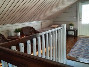 A loft bedroom with a sloped ceiling, a wooden staircase, a cushioned seating area, a small table, and a potted plant. - Loisteranta by Interhome (Ähtäri)