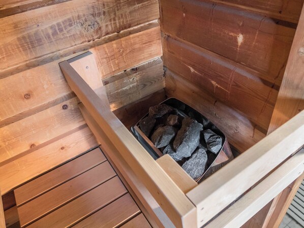 A sauna with a wooden interior, a bench, and a tray with rocks.