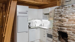 A compact kitchen with white cabinets, a built-in microwave, and a stone fireplace.