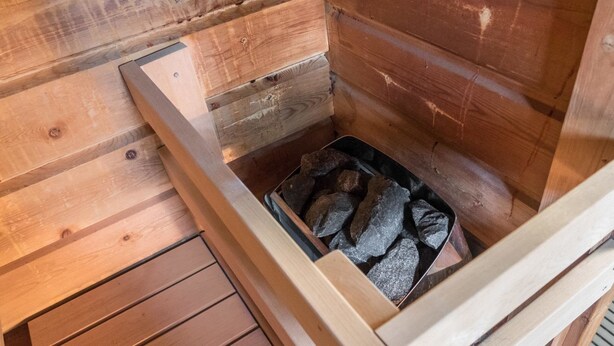 A wooden cabin interior with a metal bin containing rocks.