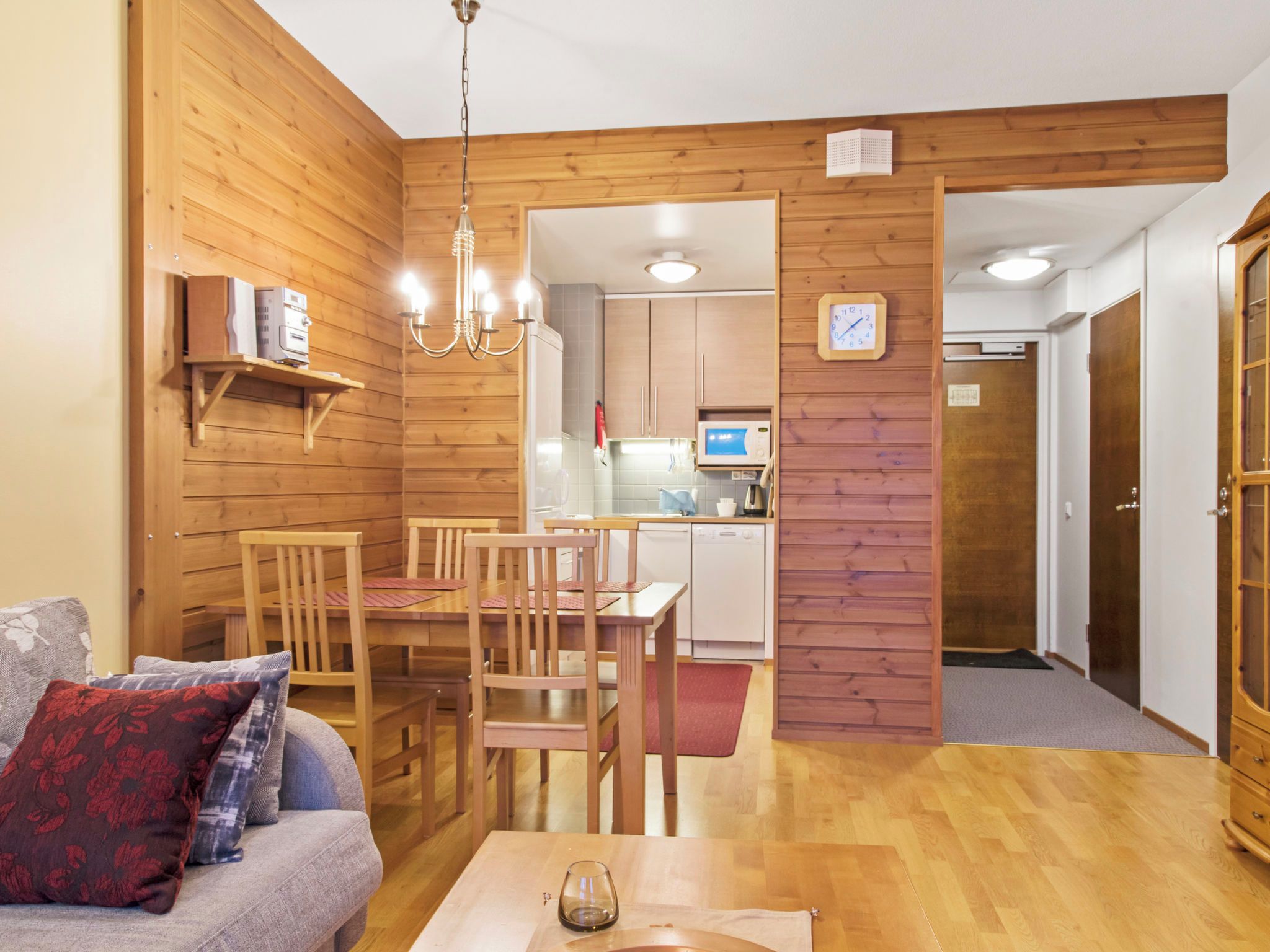 Una sala de estar acogedora con un sofá, una mesa de comedor con sillas, y una cocina visible a través de un arco.