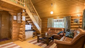 A log cabin interior with a wooden staircase, leather furniture, and a television. - Aurinkoniemi by Interhome (Hankasalmi)