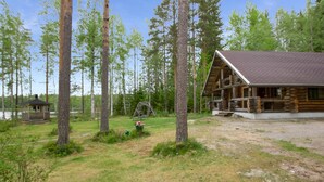 A rustic cabin with a large porch and a swing set in a wooded area. - Aurinkoniemi by Interhome (Hankasalmi)