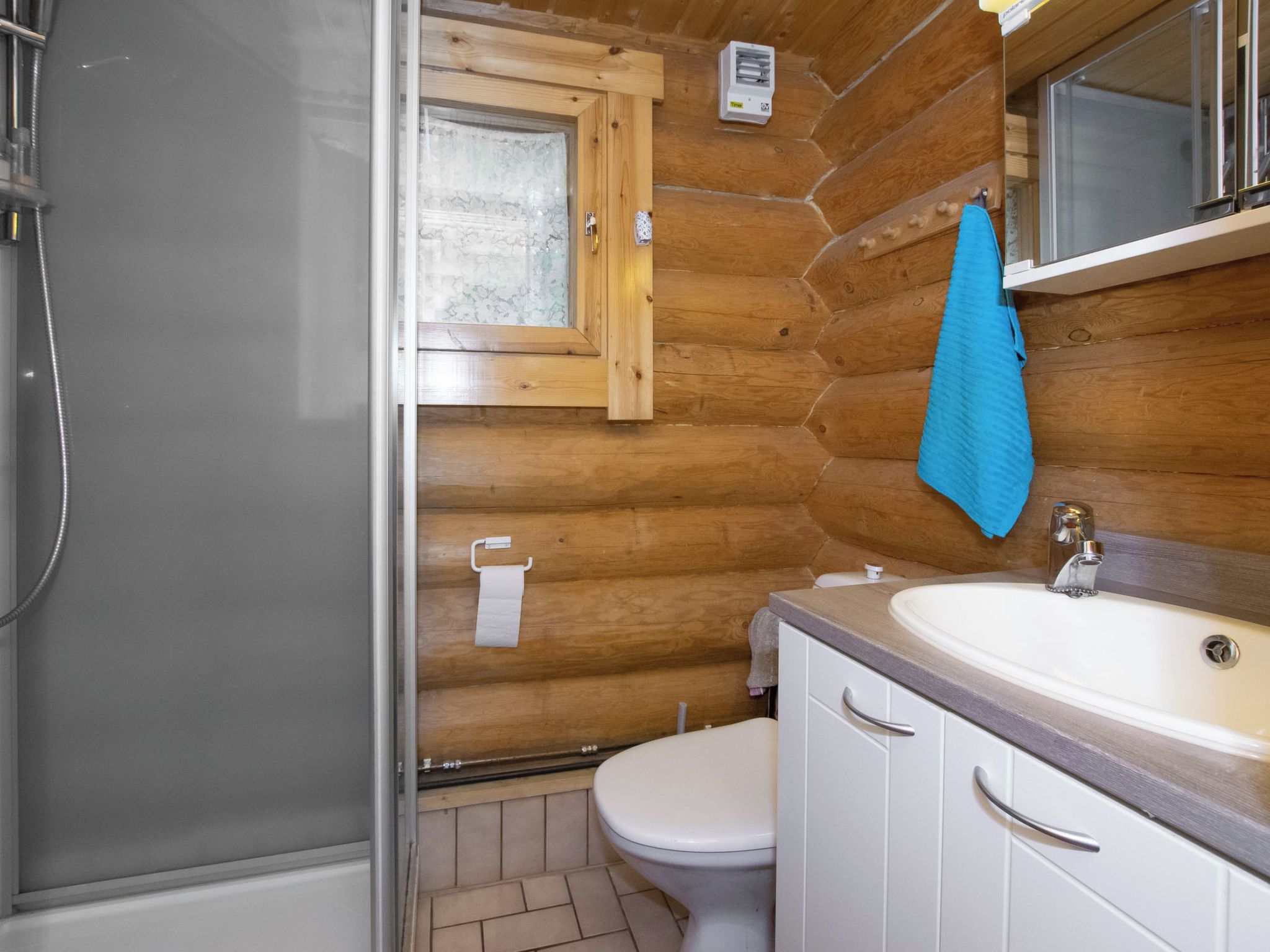 Ein Badezimmer mit einer Holzvertäfelung, einem weißen Waschbecken, einem Spiegel und einer Toilette.